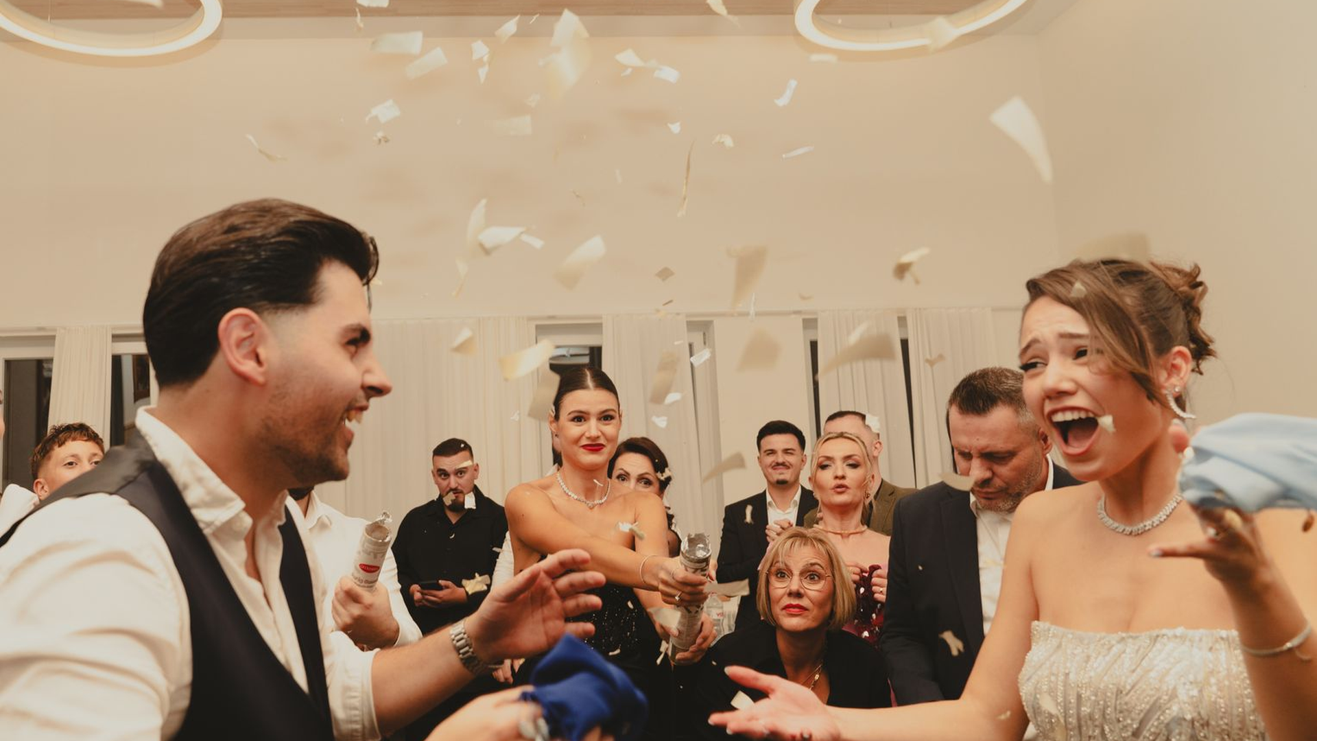 Wedding guests dancing and celebrating in a banquet hall with confetti